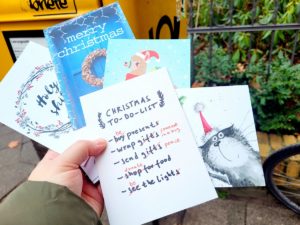 Viele Weihnachtspostkarten in einer Hand vor einem Briefkasten